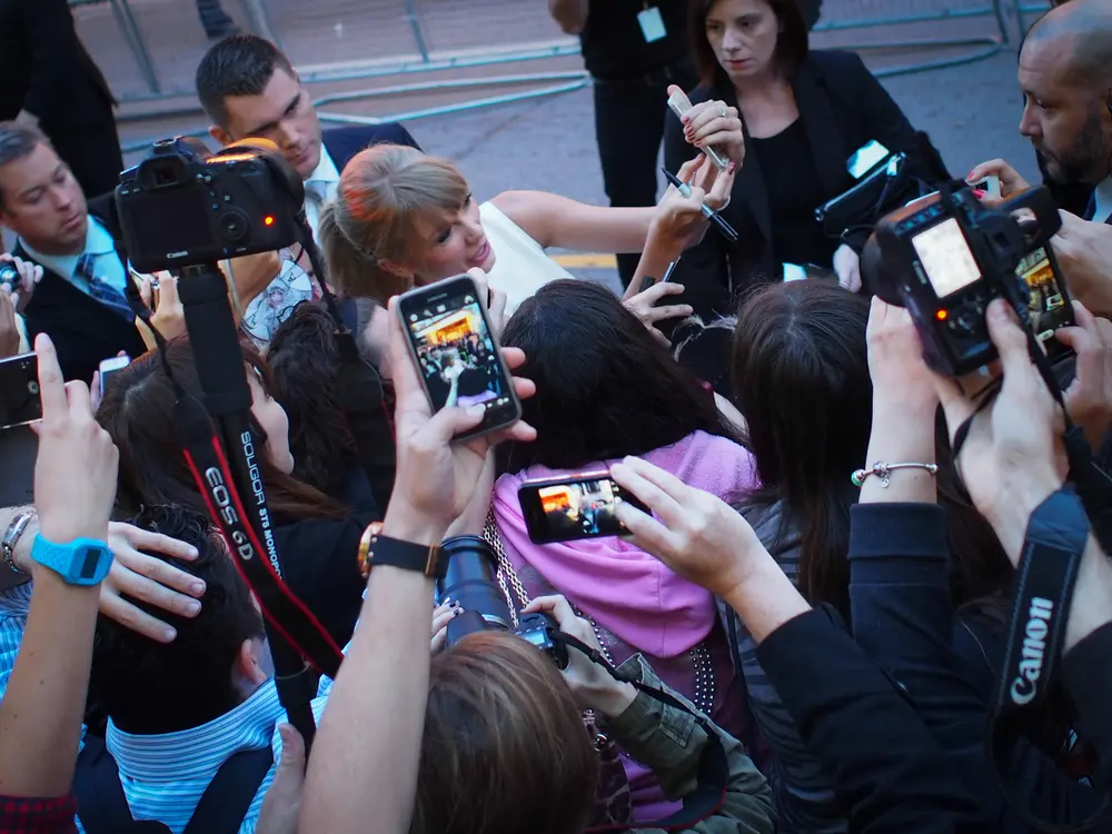 Taylor Swift greeting fans and signing autographs during a managed event arrival with security and media presence
